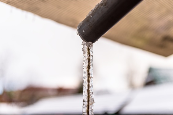 melting icicle hanging from building in winter